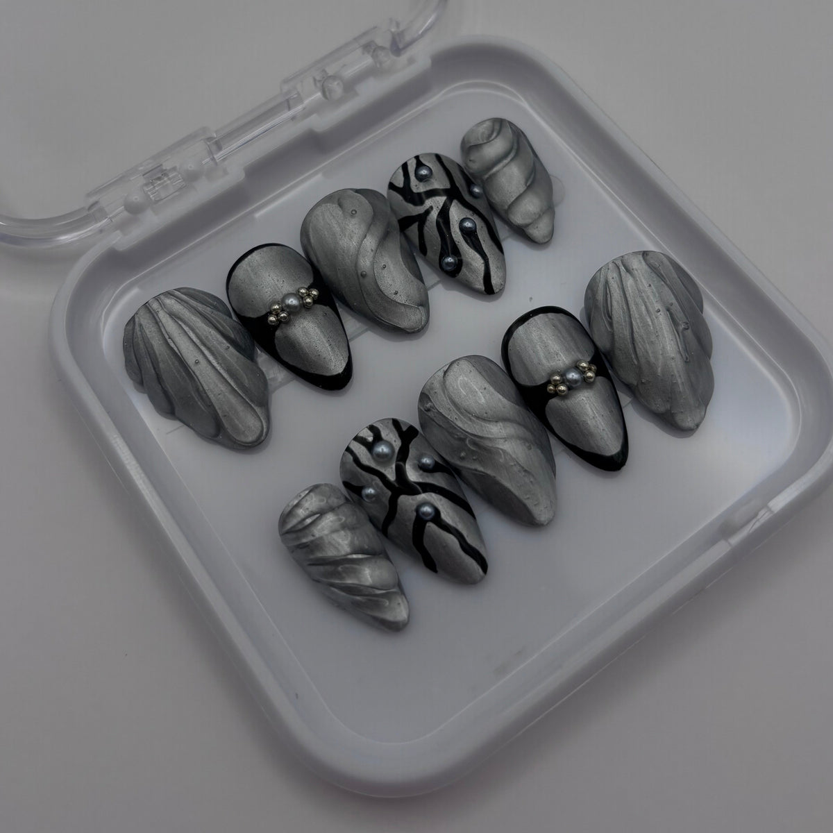 Extensions d'ongles press on Joy Chrome 3D de Onailsbymanon, finition chromée brillante et design en relief 3D.
