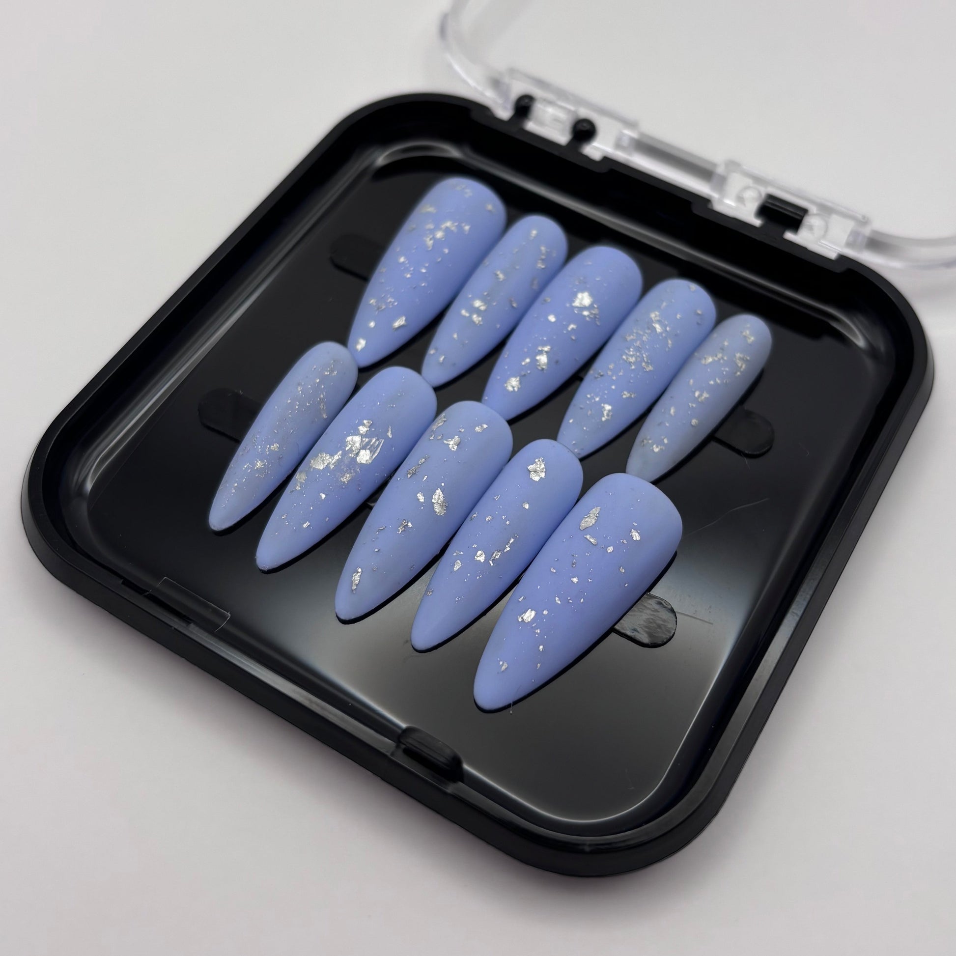Flocons d'argent Azélia de Onailsbymanon, vernis press-on pour ongles, visibles sur fond blanc.