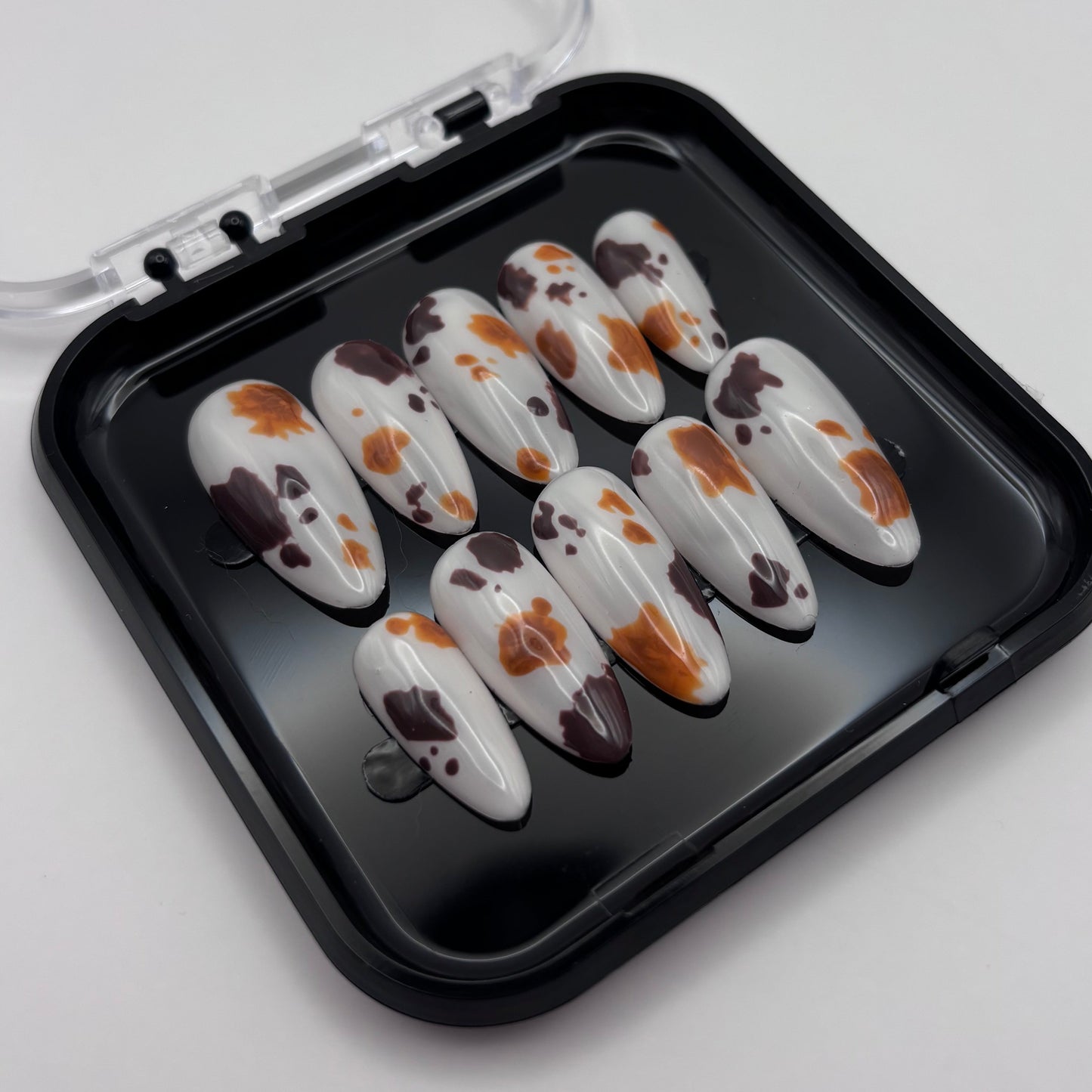 Extensions de faux ongles Sienna en motif vache, press-on de la marque Onailsbymanon, visibles dans cette image.