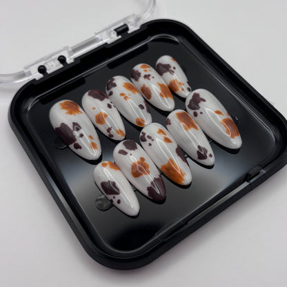 Extensions de faux ongles Sienna en motif vache, press-on de la marque Onailsbymanon, visibles dans cette image.